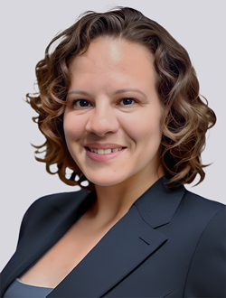 Smiling professional woman in a suit with curly hair, on a neutral background.