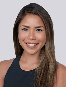 Portrait of a smiling woman with long hair in a black top against a plain background.