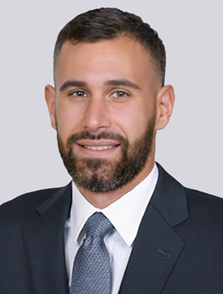 Professional man in a suit and tie, smiling with a neutral background. Perfect for corporate or business profiles.