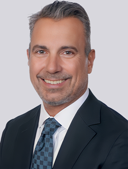 Professional man in a suit smiling against a neutral background, ideal for business profiles or corporate presentations.