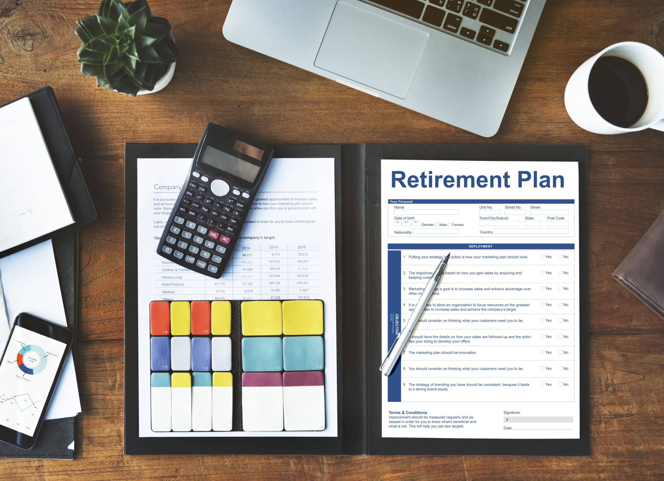 Retirement plan documents on a desk with a calculator, pen, and laptop for financial planning and analysis.