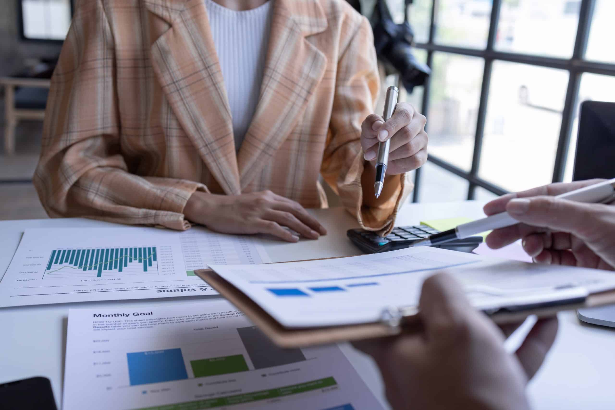 Business meeting with charts and graphs, discussing financial goals and strategies at office desk.